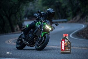 Una moto Kawasaki Z500 encara unca curva. Debajo, a la derecha de la imagen, un pote de aceite.
