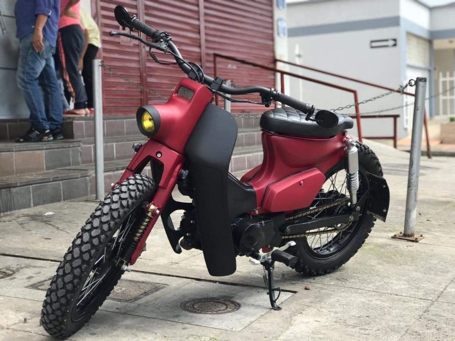 Una moto 110 modificada y pintada de color borravino