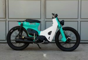 Una moto 110 modificada totalmente y pintada de color turquesa y blanco