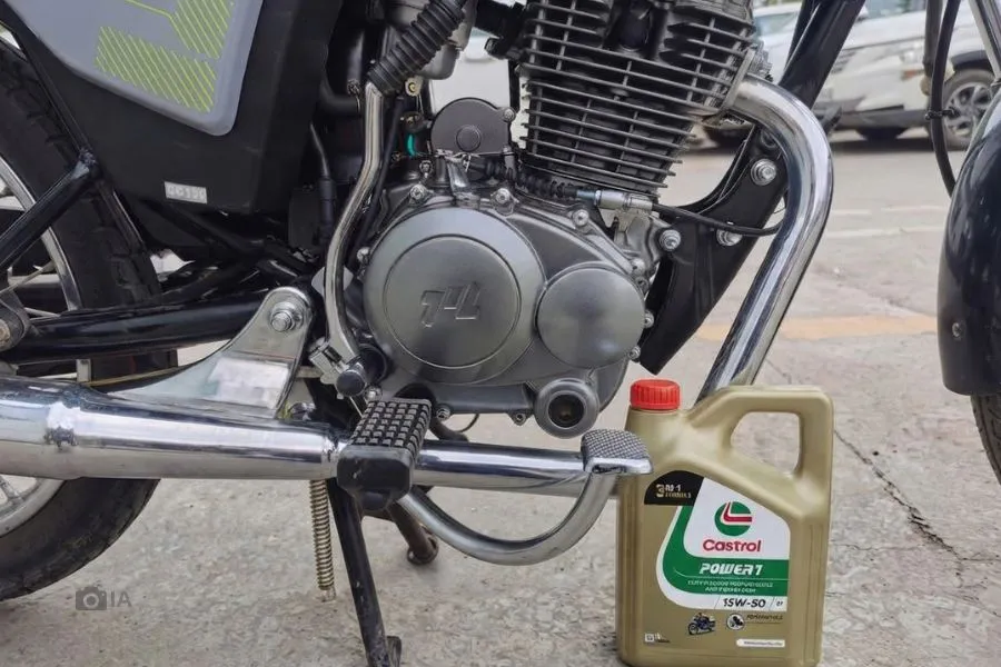 Primer plano del motor de una Motomel S2 150 junto a un bote de aceite