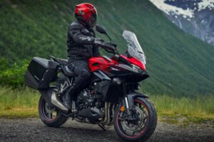 Un motociclista mira el paisaje montañoso sobre su moto touring roja y negra