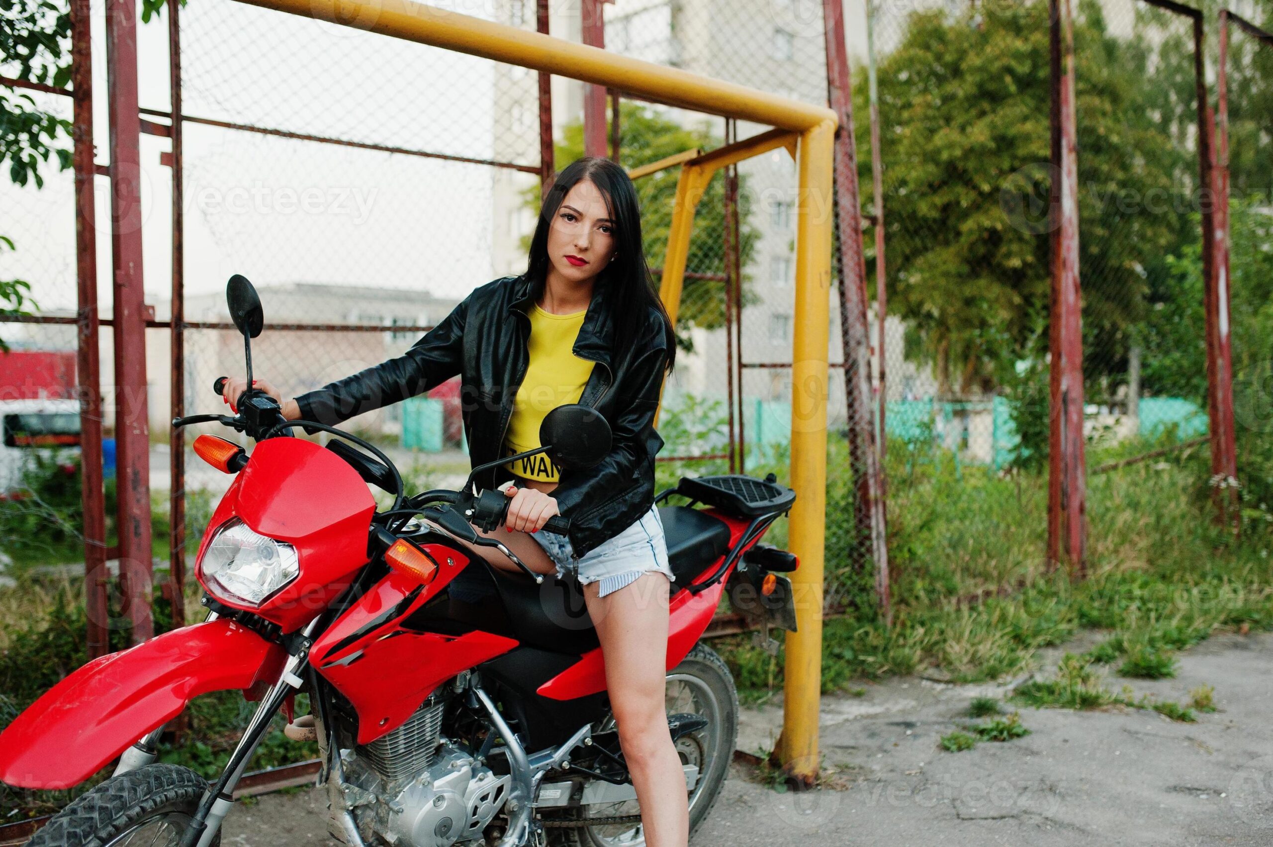 Una mujer mira a la cámara sentada sobre su moto enduro roja y negra